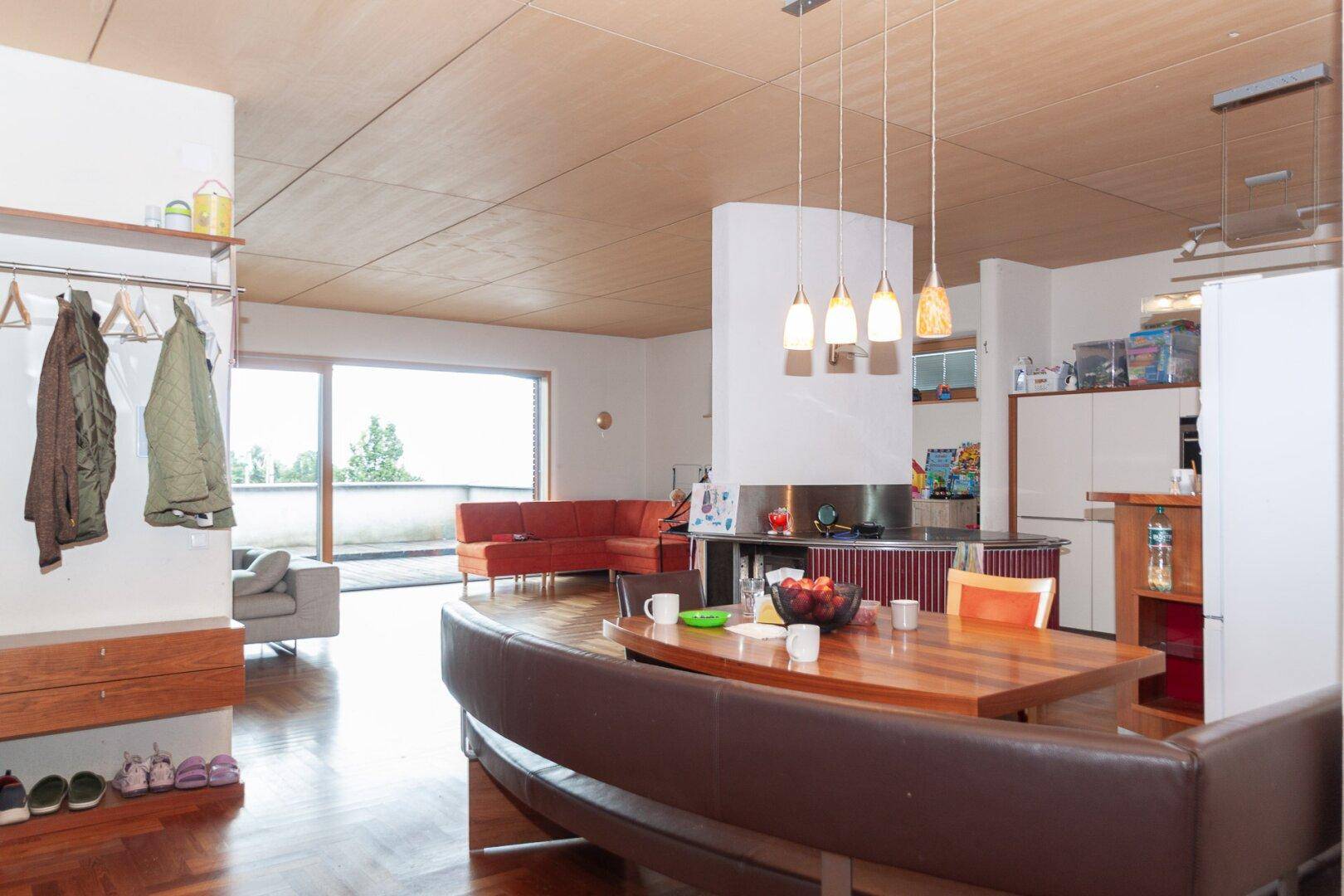 Offener Wohn-Essbereich mit Holzboden, Esstisch, Sofa und Zugang zur Terrasse.