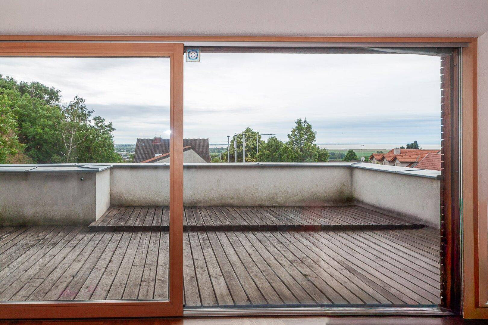 Geräumige Holzterrasse mit weitem Blick über die Landschaft und den Horizont.
