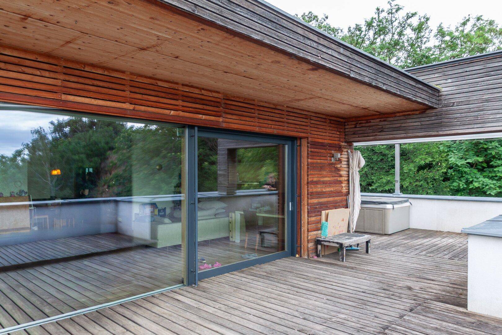 Holzterrasse mit großen Glasschiebetüren, die den Innenraum mit dem Außenbereich verbinden.