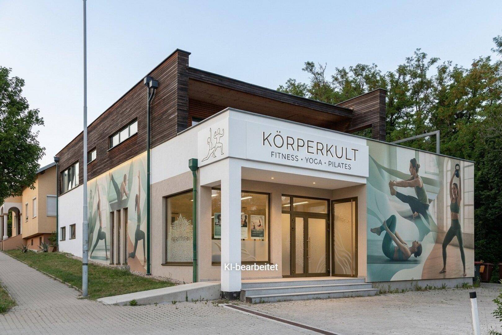 Geschäftsgebäude mit moderner Fassade und großflächiger Werbung für Fitness, Yoga und Pilates.