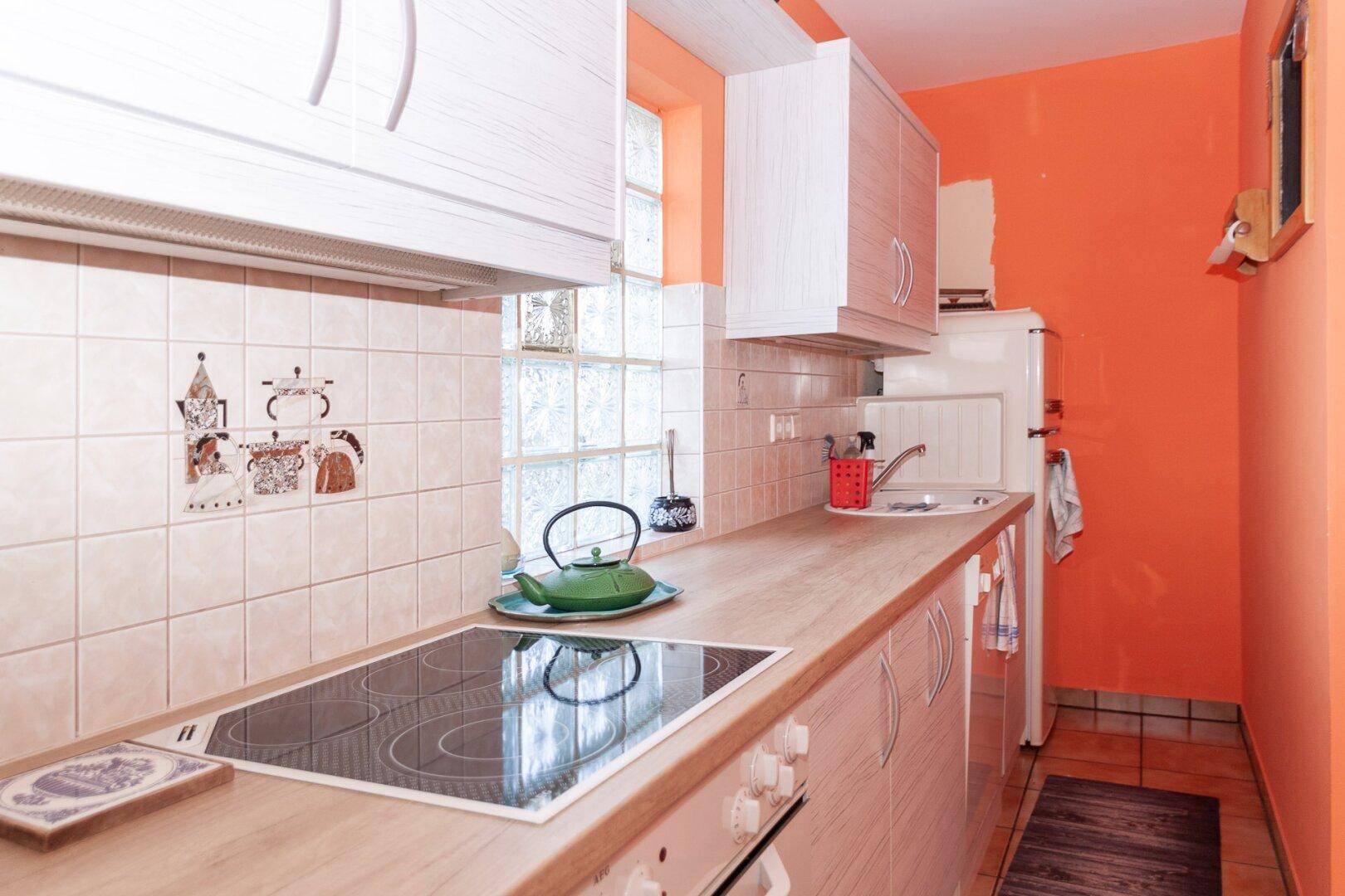 Detailansicht der Küche mit Induktionskochfeld, Spüle und gefliestem Spritzschutz.