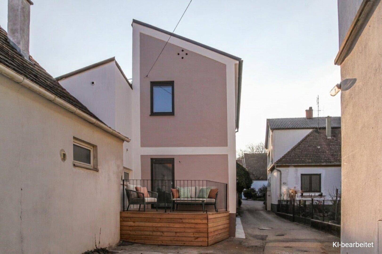 Moderne Hausfassade mit kleiner Holzterrasse und Sitzgelegenheiten im Freien.