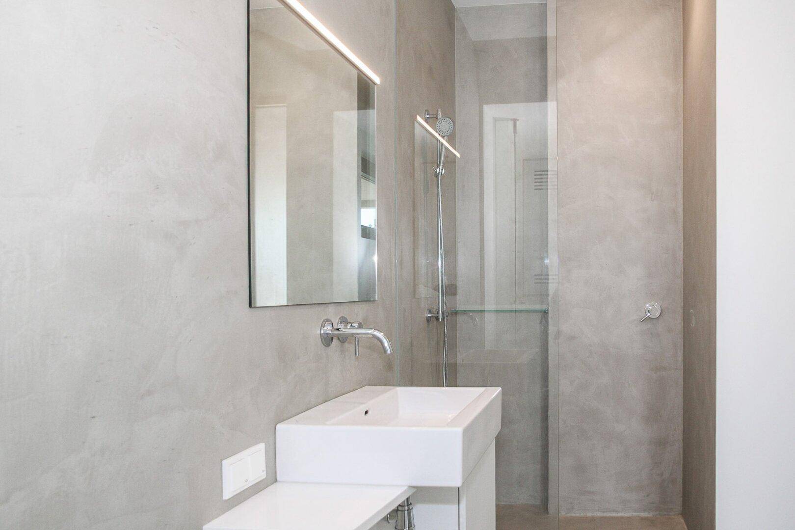Modernes Badezimmer mit minimalistischem Design, großformatigen Fliesen und begehbarer Dusche.