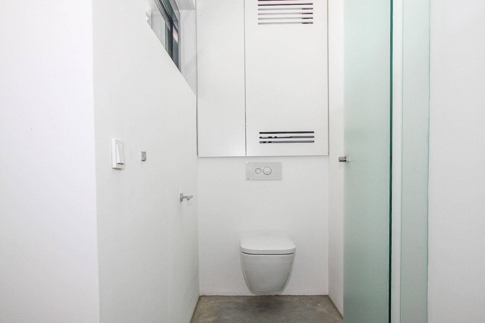 Modernes WC mit wandhängender Toilette und minimalistischer Gestaltung in Weiß.