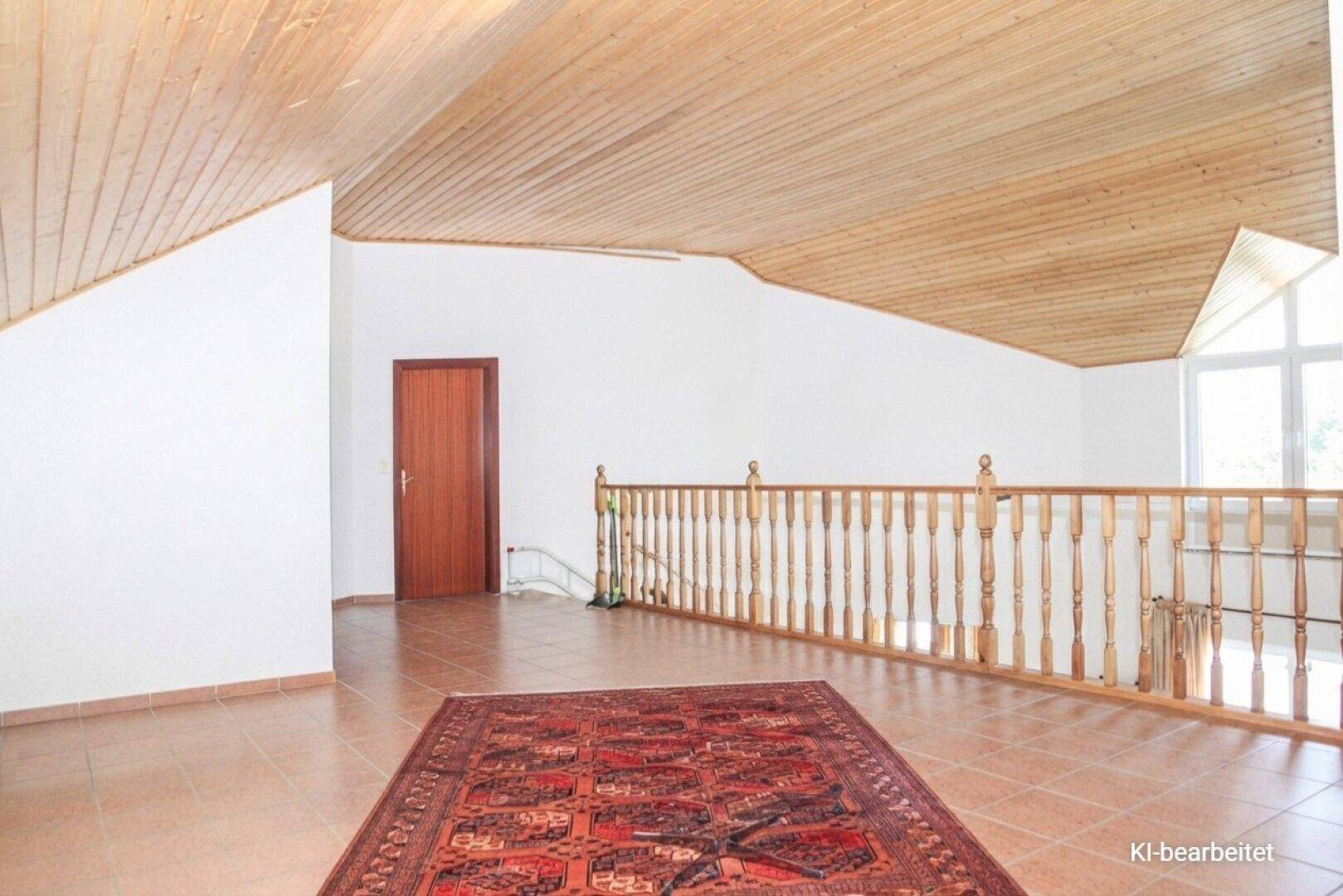 Heller Dachbodenbereich mit Holzverkleidung an der Decke und Teppich auf Fliesenboden.