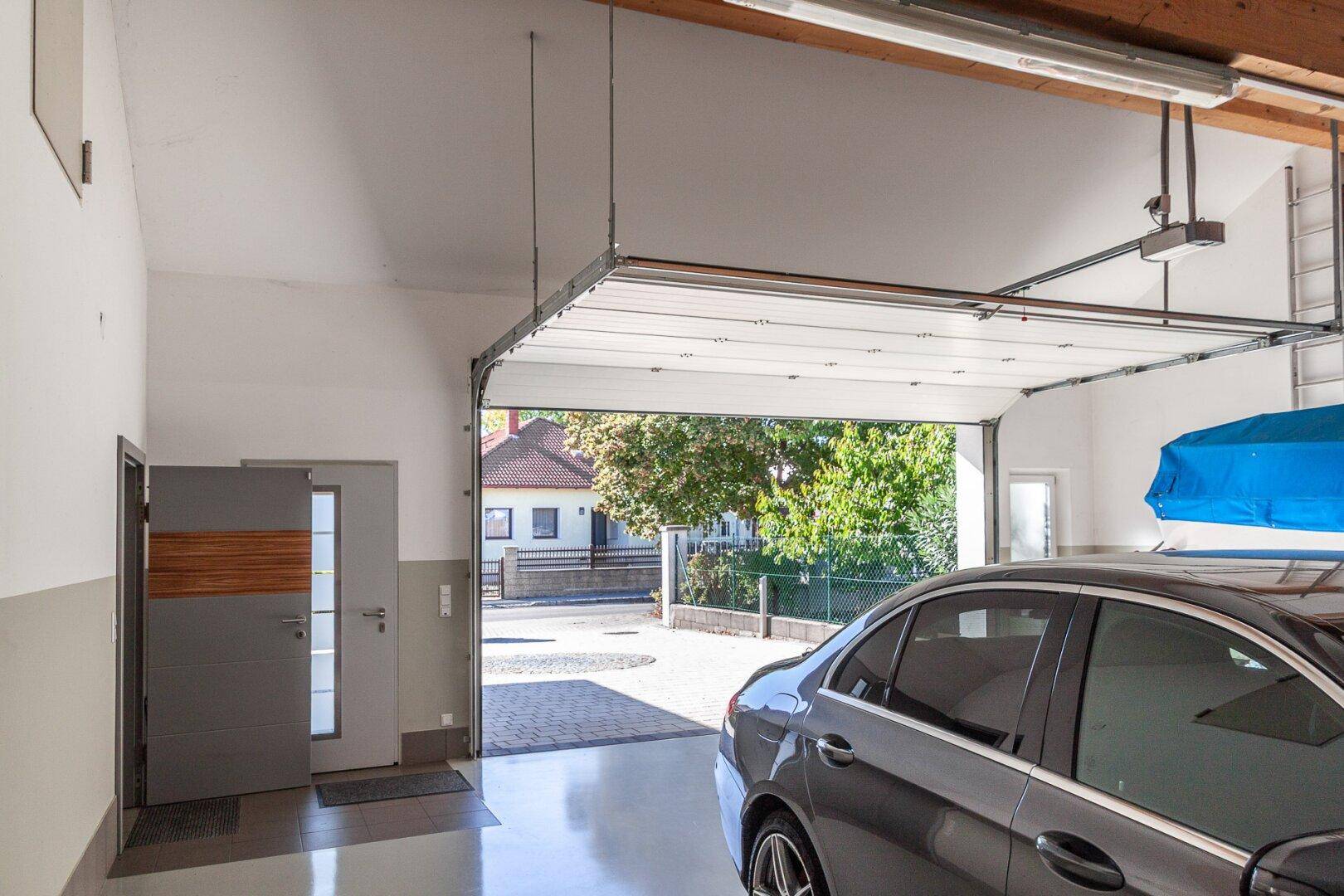 Geräumige Garage mit offenem Tor, geparktem Auto und Blick auf die Straße.