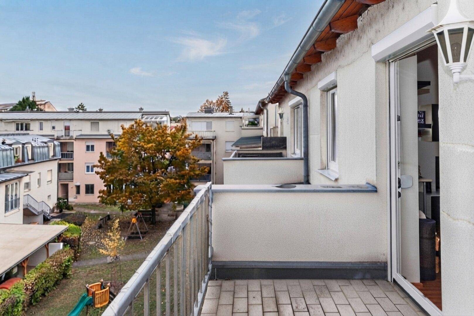 Balkon mit Blick auf einen Gemeinschaftsgarten und umliegende Gebäude.