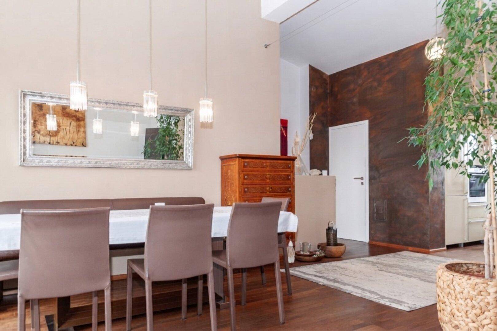 Essbereich mit Holzboden, Spiegel und einer dekorativen Wand in Erdtönen.