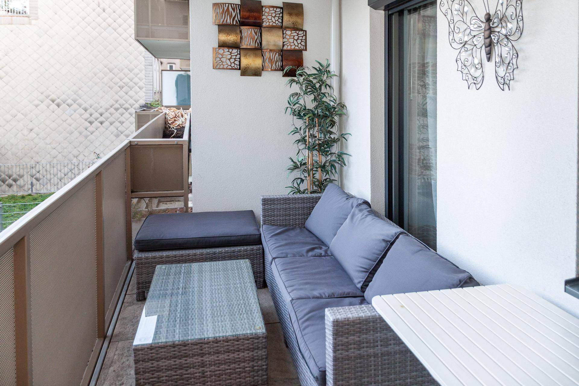 Möblierter Balkon mit Rattan-Sitzgruppe und dekorativen Elementen für entspannte Stunden.