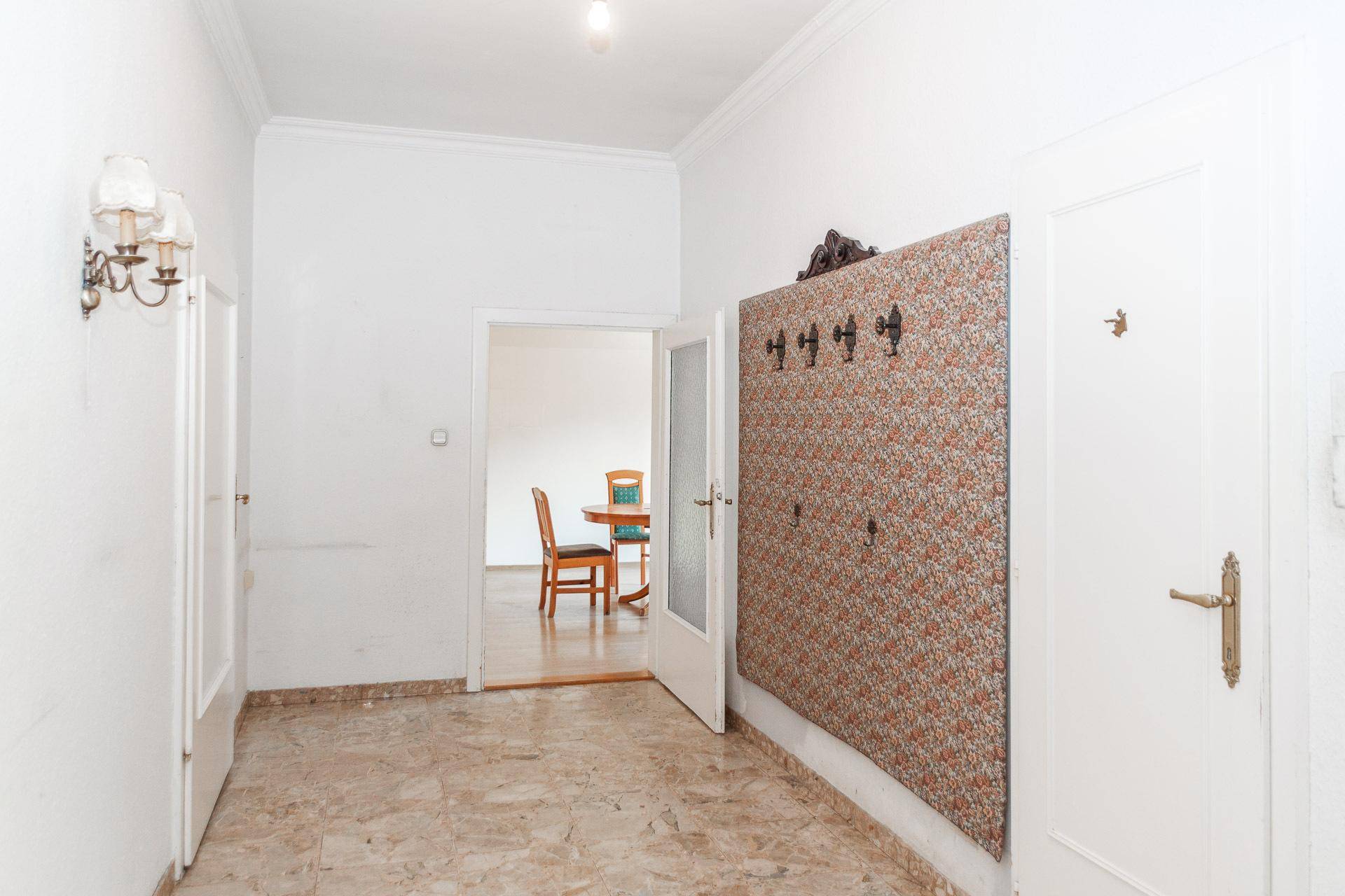 Heller Flur mit Marmorboden und Garderobe, der zu weiteren Räumen führt.