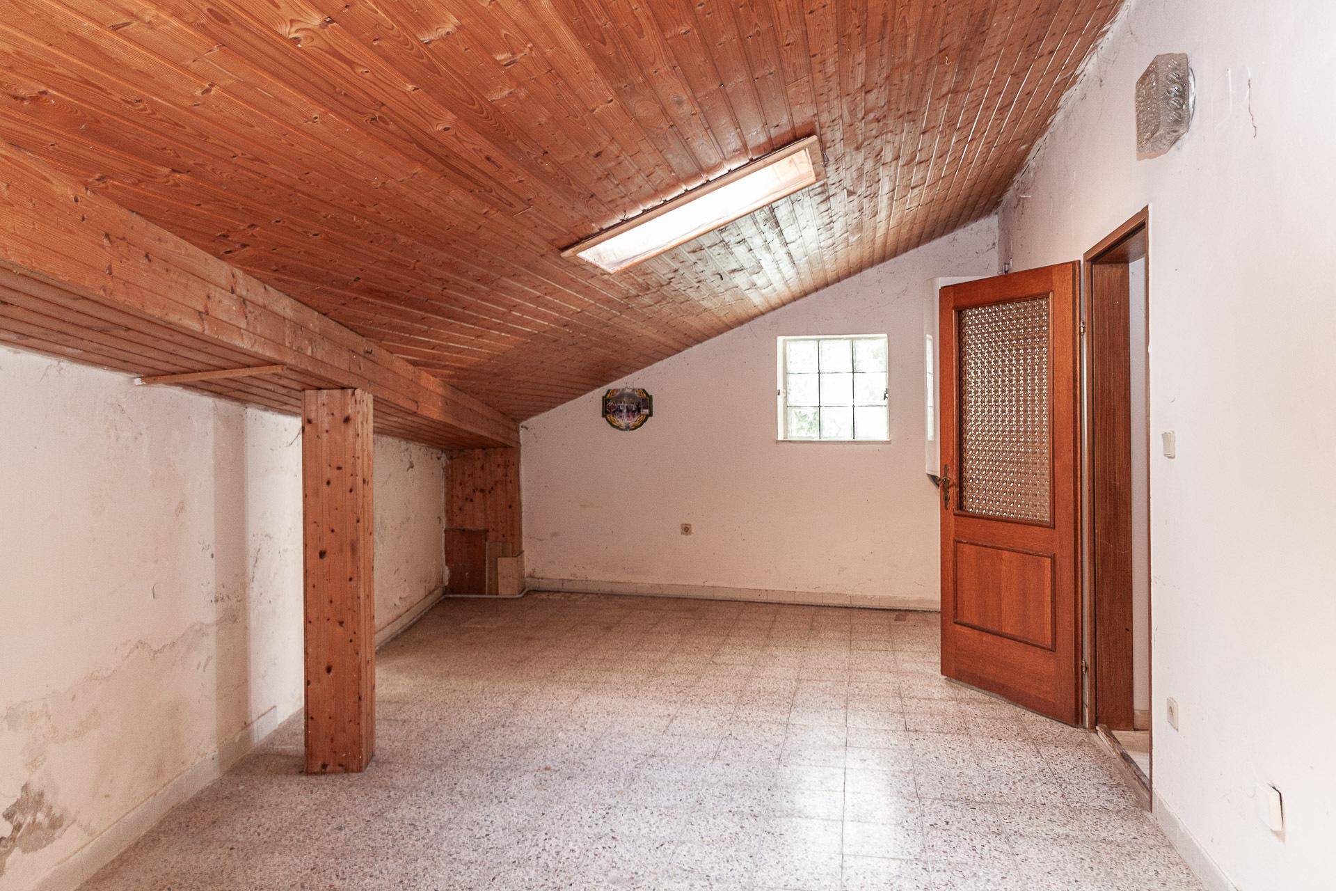 Geräumiger Dachboden mit Holzdecke und Fenster, ideal als Abstellraum oder Ausbaufläche.