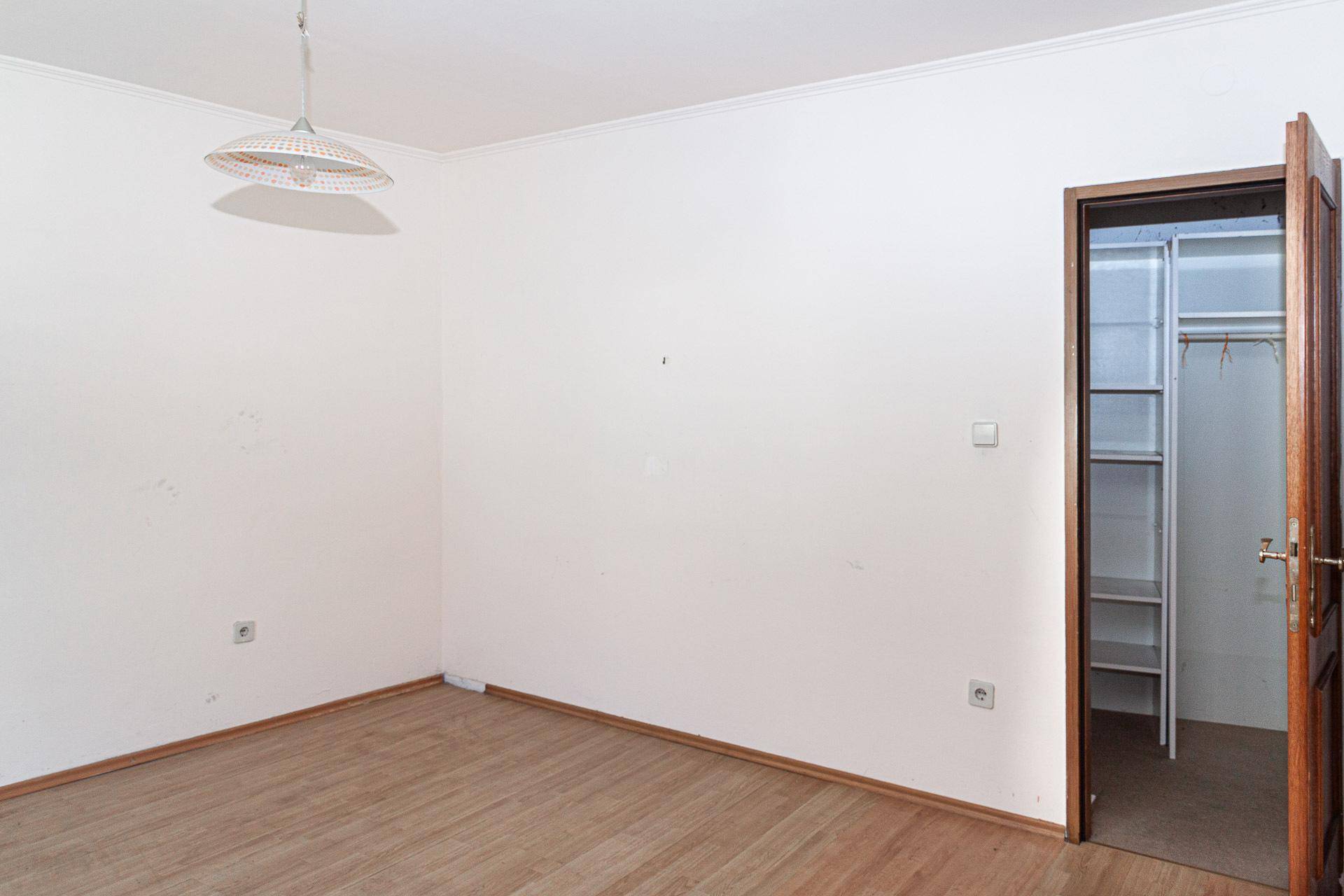 Schlafzimmer mit Laminatboden und Zugang zu einem begehbaren Kleiderschrank.