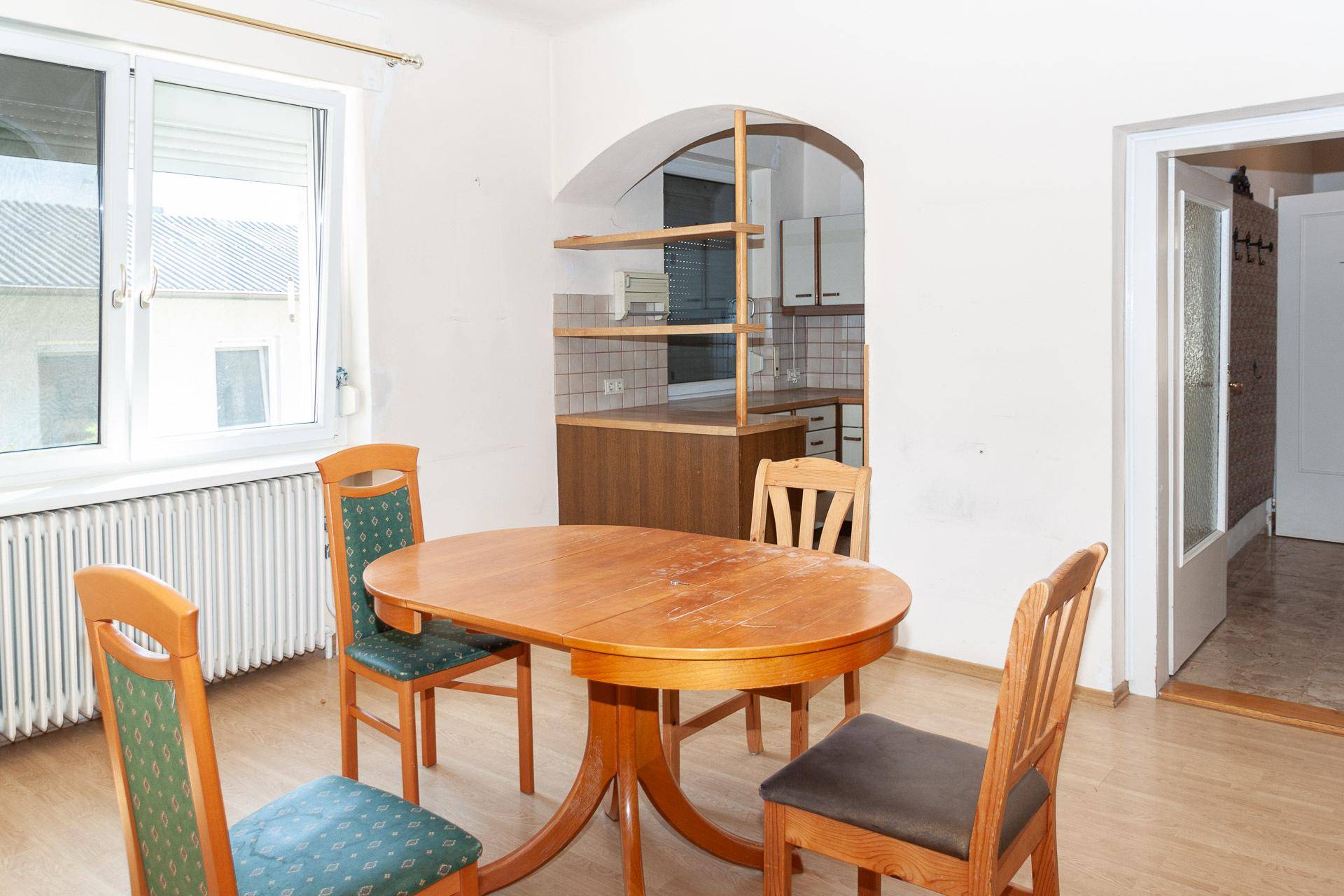 Essbereich mit Holztisch und Blick in die angrenzende, halb offene Küche.