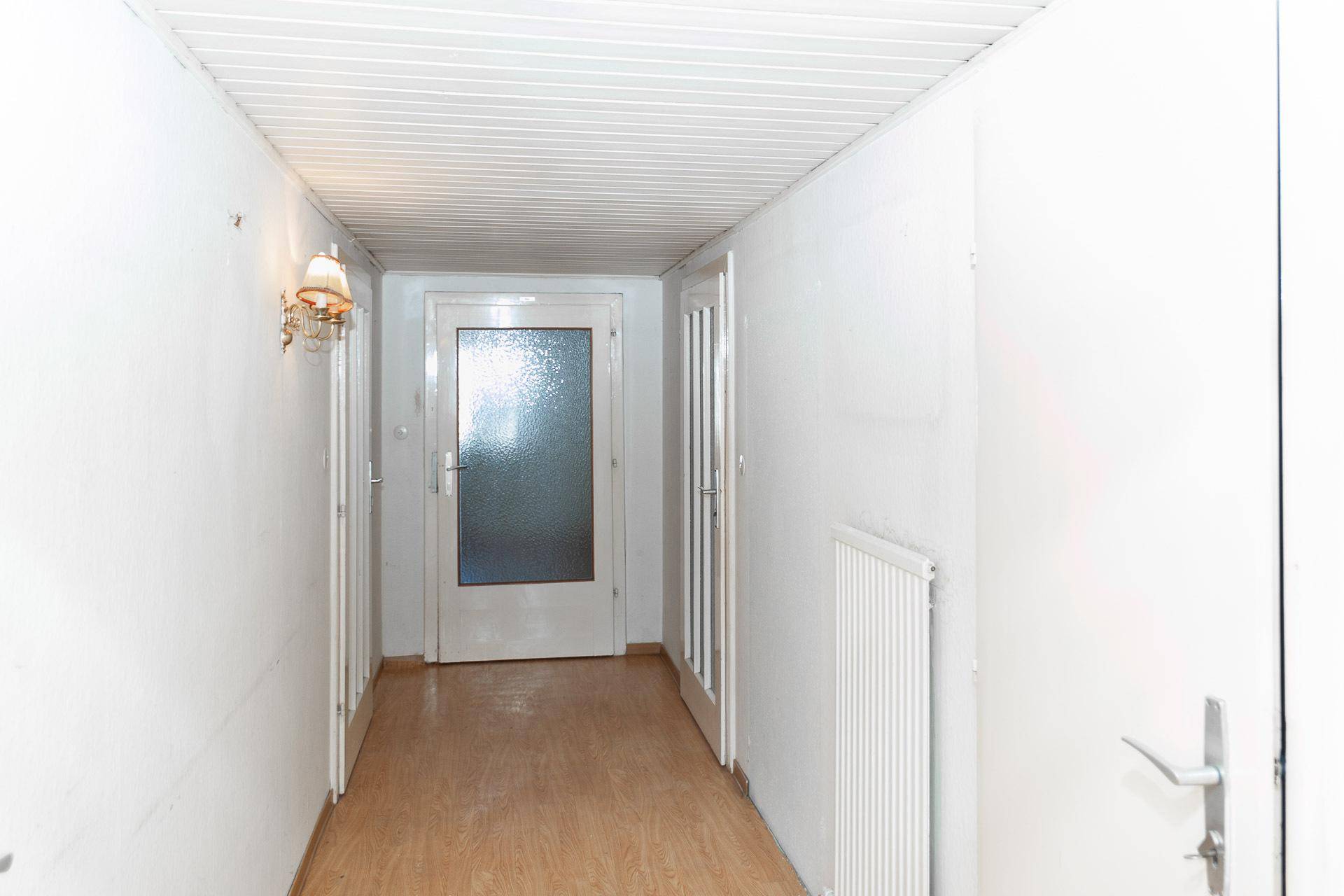 Langer Flur mit Holzdecke und hellem Boden, der zu mehreren Zimmern führt.