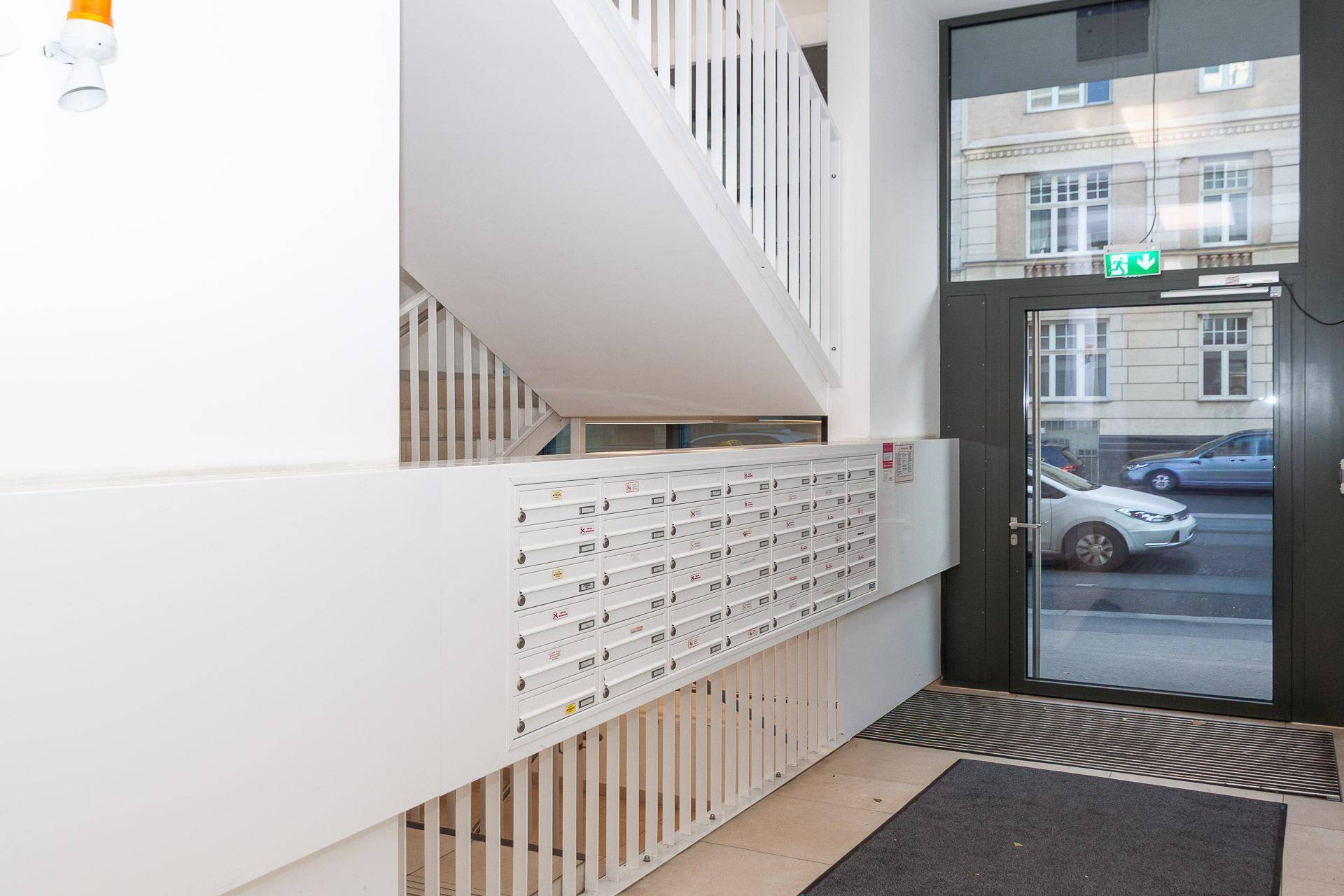 Heller Eingangsbereich eines Mehrfamilienhauses mit Briefkästen und Blick auf die Straße.