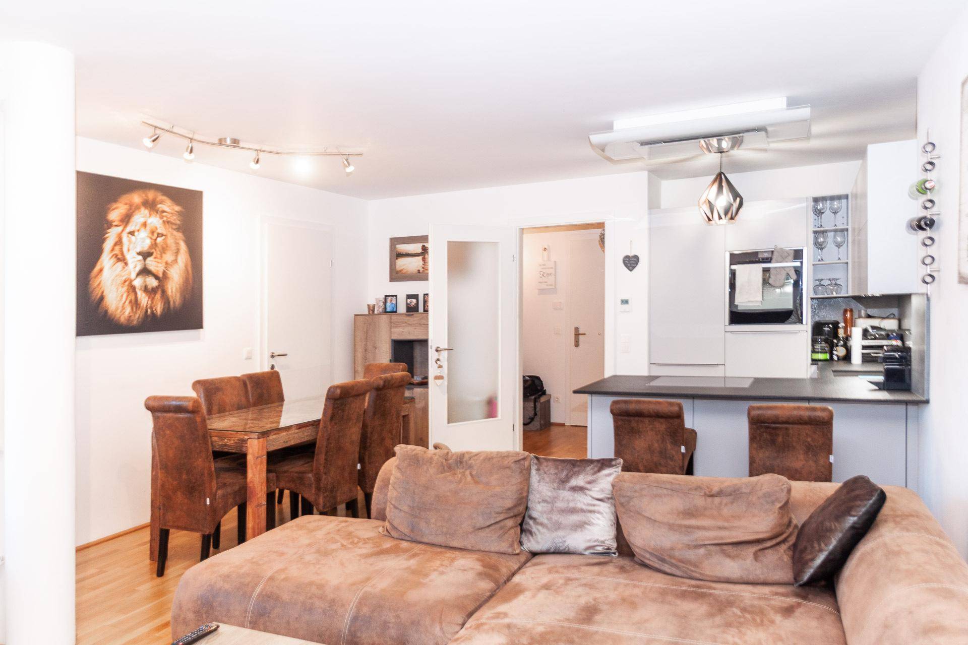 Gemütlicher Wohn- und Essbereich mit offener Küche, Holzboden und moderner Einrichtung.