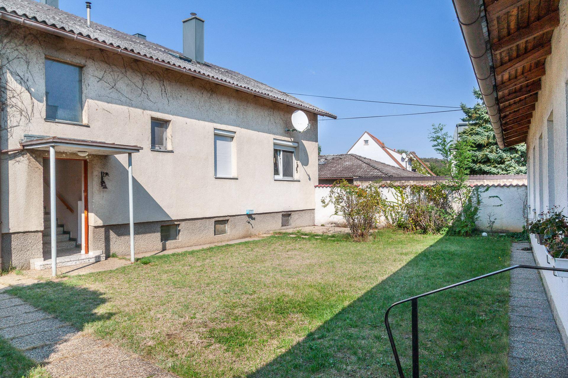 Großer Gartenbereich hinter dem Haus mit Rasenfläche und Zugang zum Gebäude.
