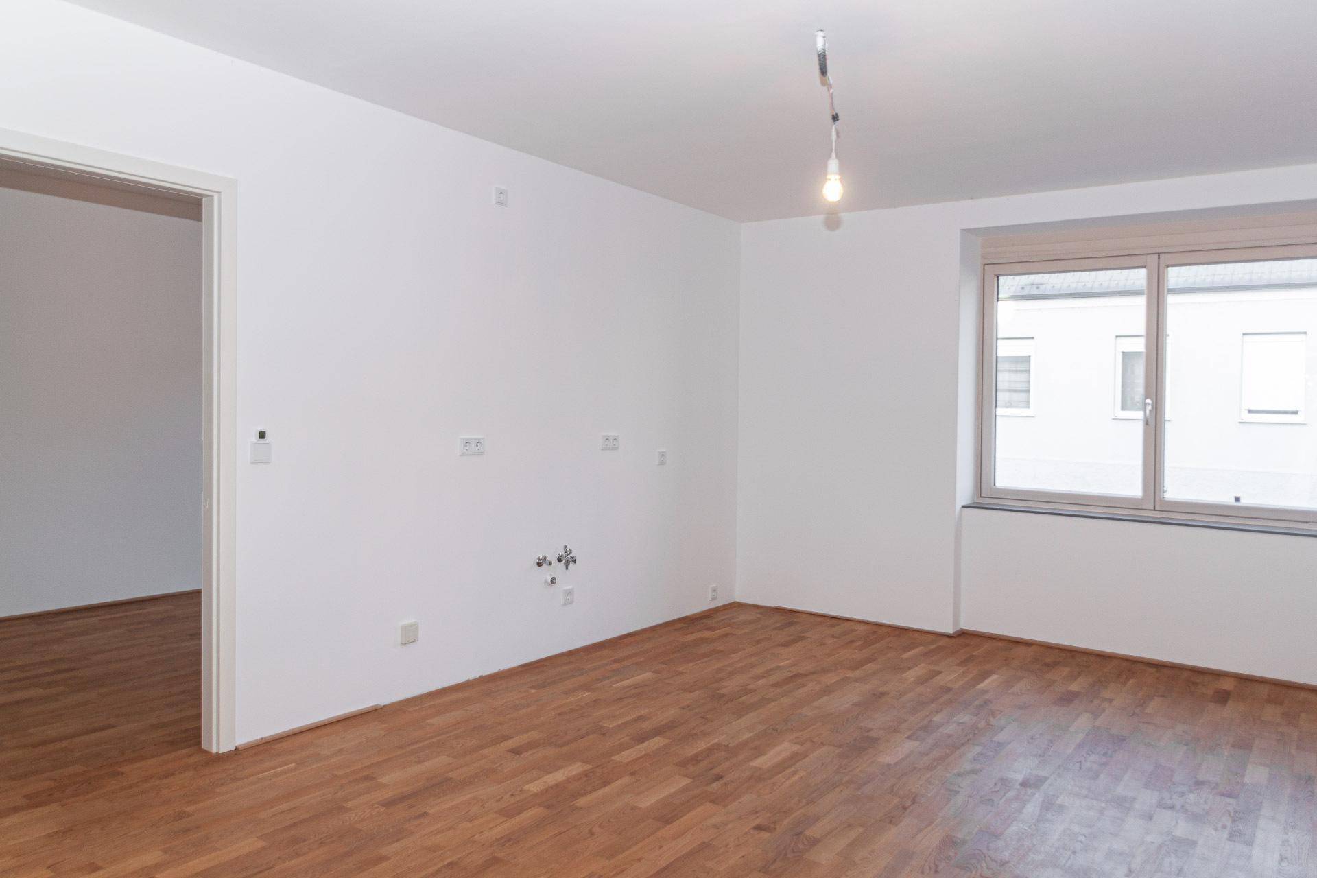 Geräumiger, heller Raum mit Holzboden und Fenster, bereit für individuelle Gestaltung.