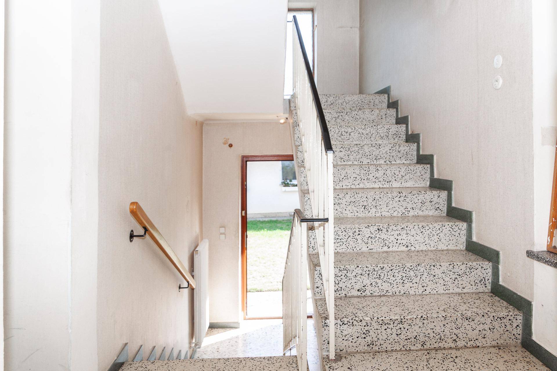 Treppenhaus mit Terrazzostufen und Geländer, das die verschiedenen Etagen verbindet.