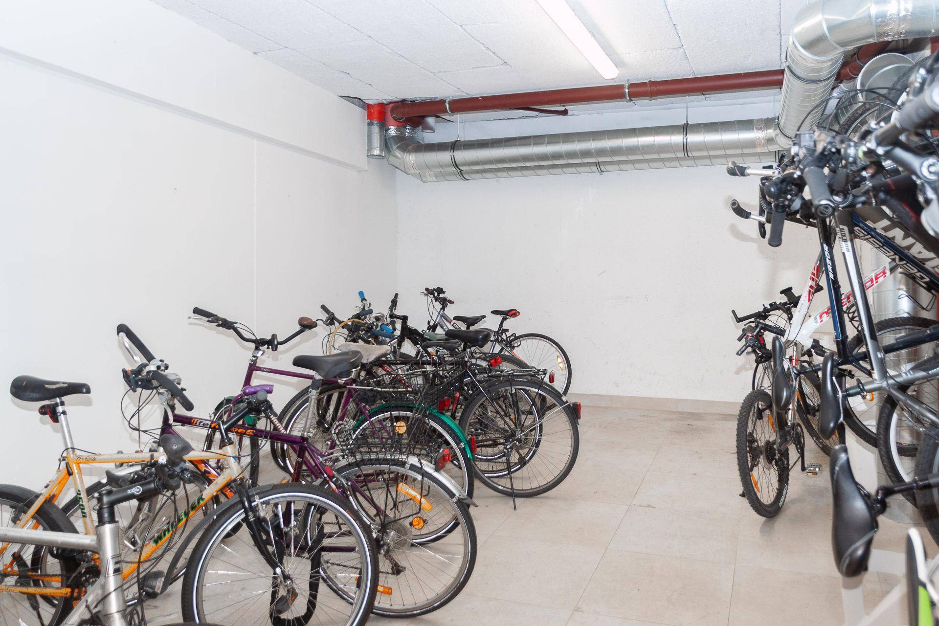 Fahrradraum im Untergeschoss mit zahlreichen Fahrrädern und Stauraum.