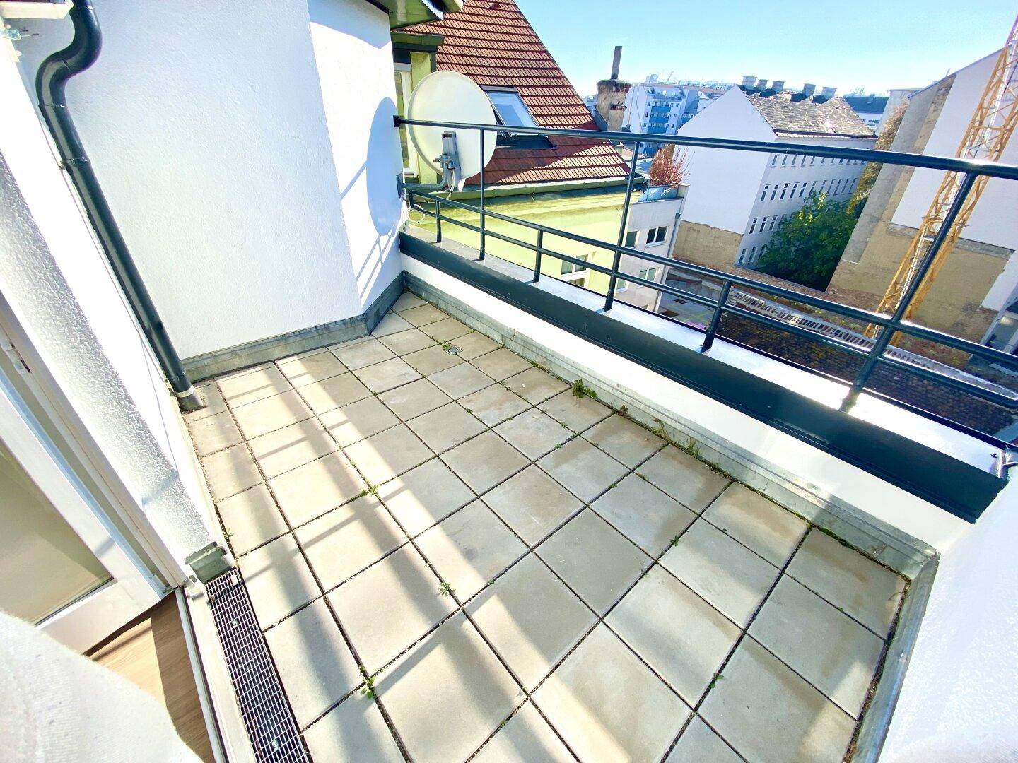 Geräumige Terrasse mit Fliesenboden und Blick über die Dächer der Stadt.