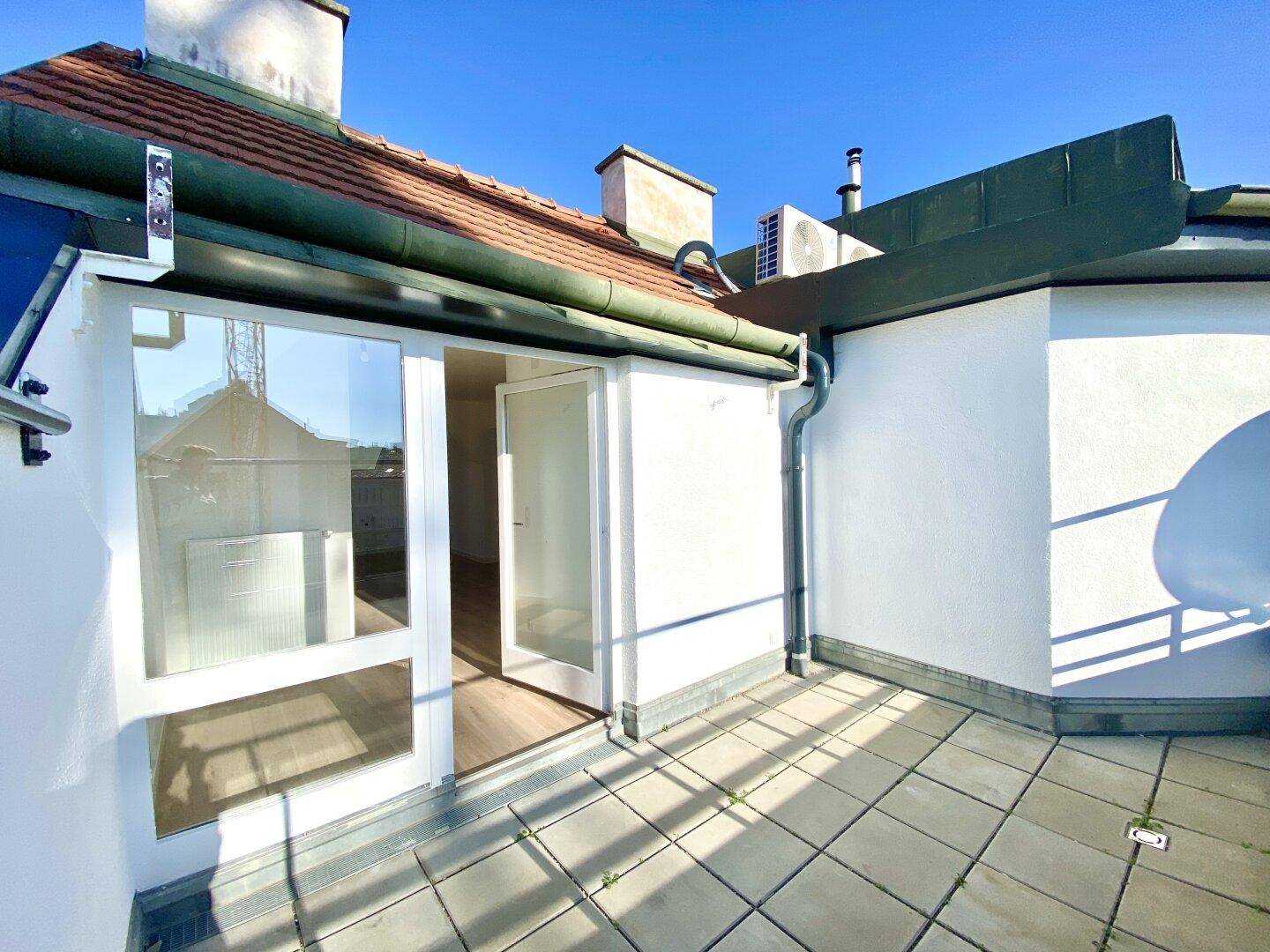 Helle Terrasse mit Fliesenboden und direktem Zugang zum Innenbereich der Wohnung.