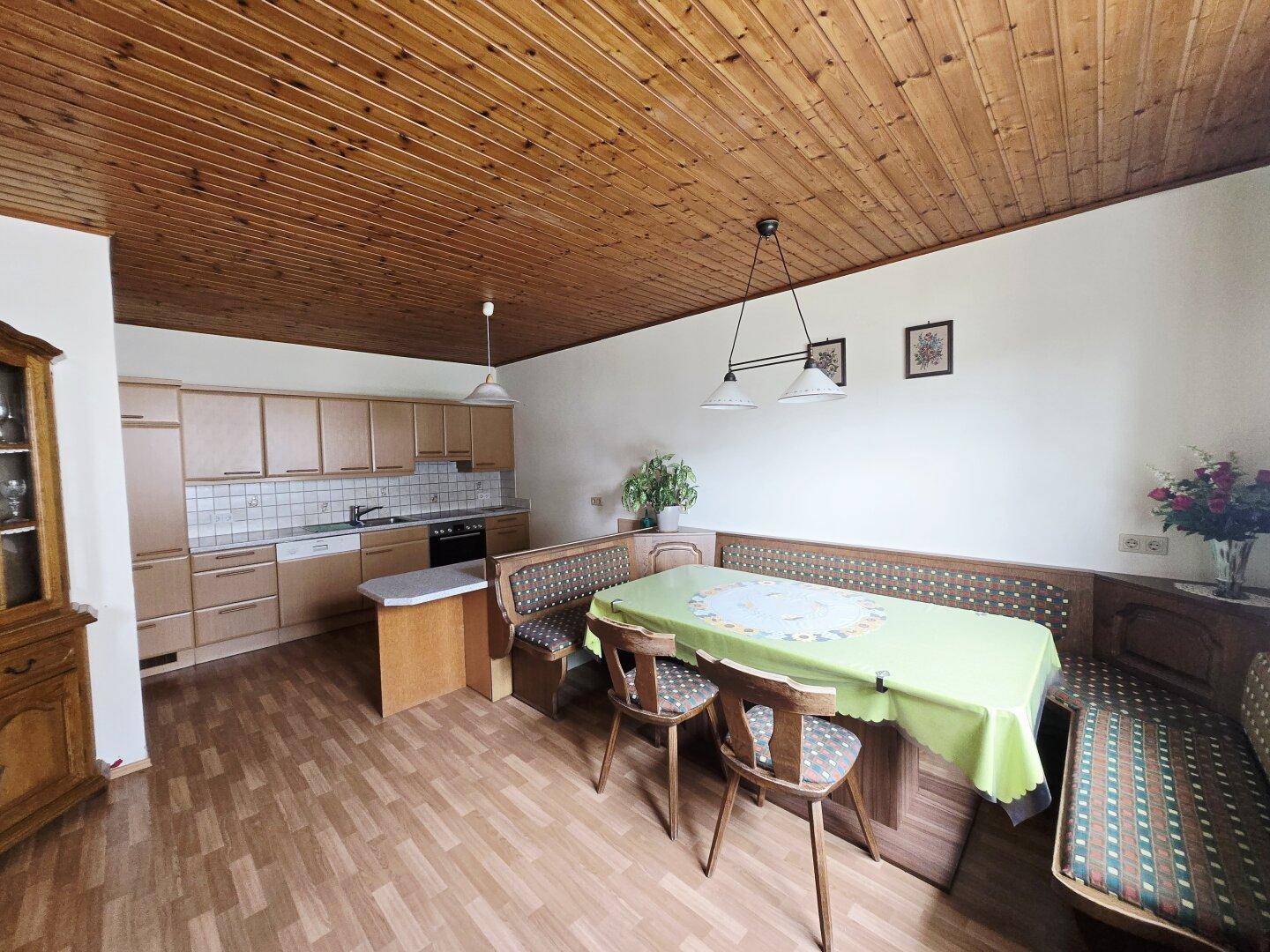 Geräumige Wohnküche mit Holzdecke, Einbauküche und einer Eckbank für gemeinsame Mahlzeiten.