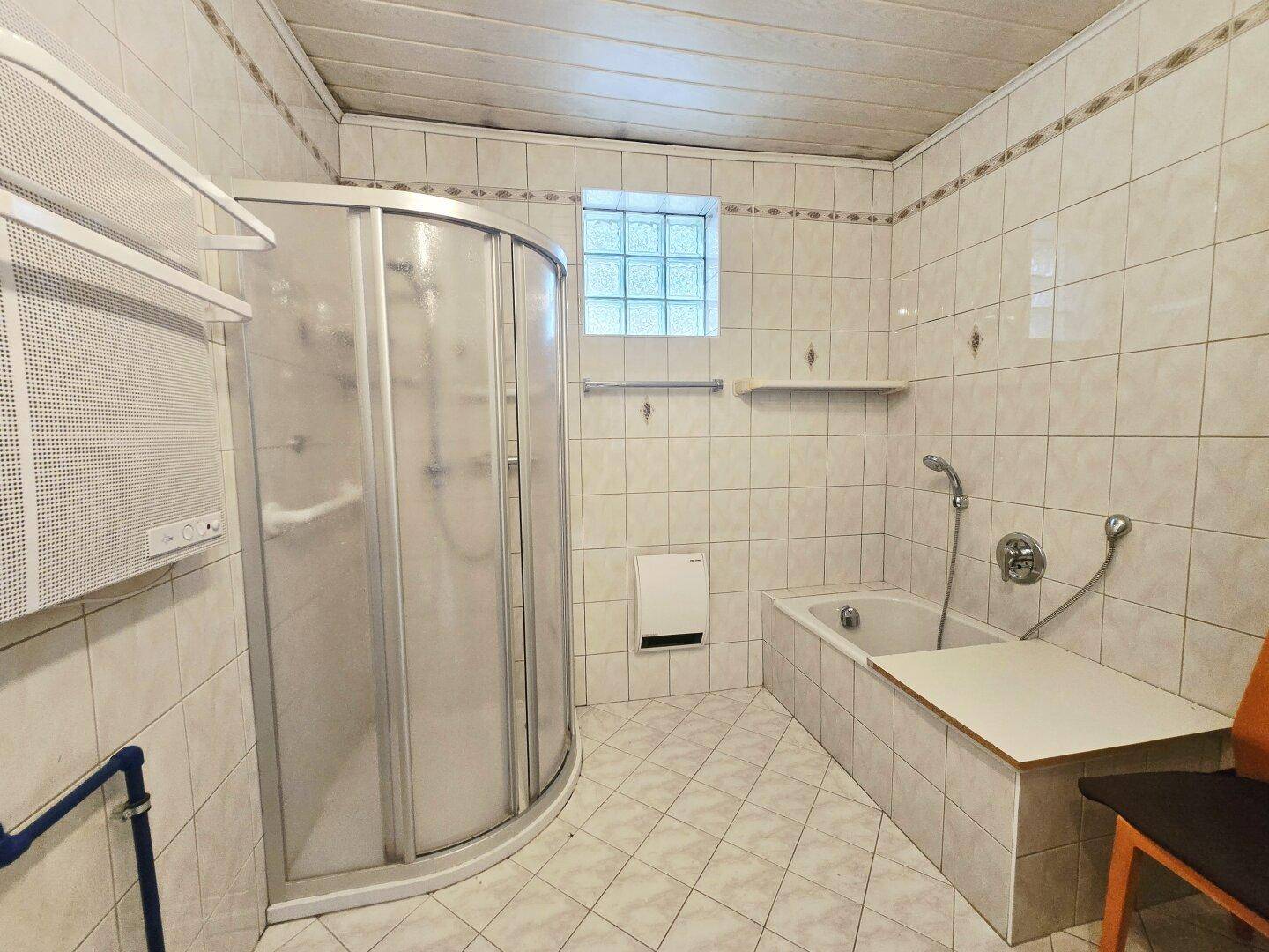 Badezimmer mit Badewanne, Duschkabine und Fliesen an Wänden und Boden.