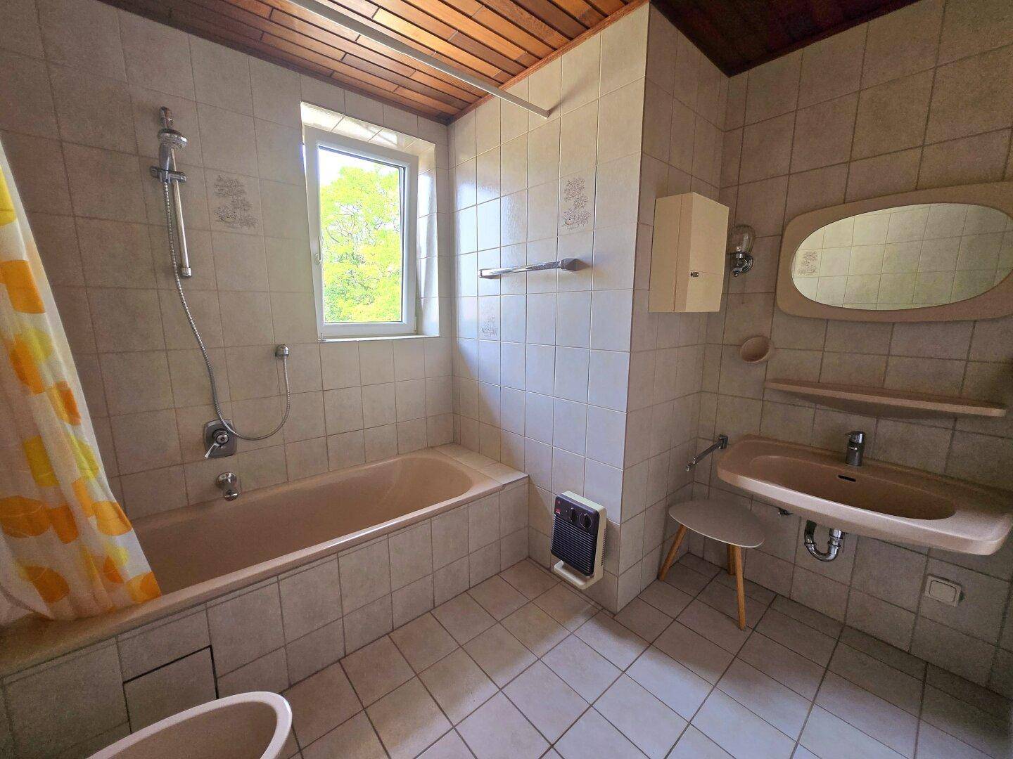 Badezimmer im 80er-Jahre-Stil mit Badewanne, Waschbecken und Fenster.