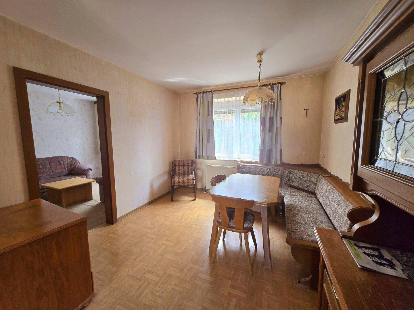 Esszimmer mit Laminatboden, Eckbank und einem Fenster mit Blick nach draußen.