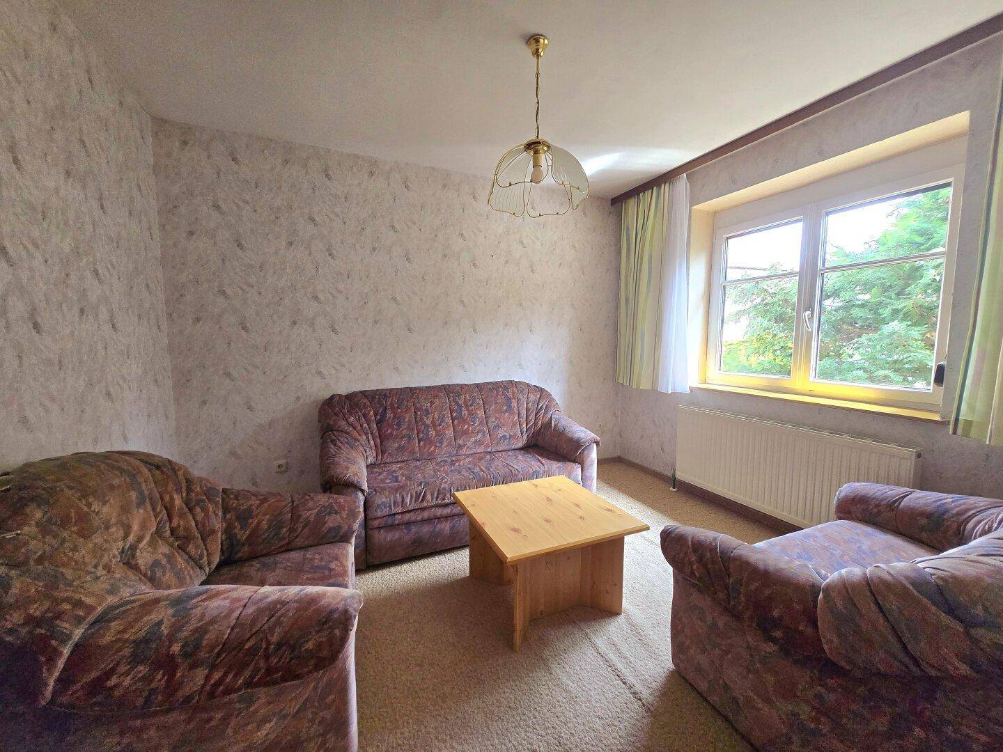 Gemütliches Wohnzimmer mit Teppichboden, zwei Sofas und einem Fenster.
