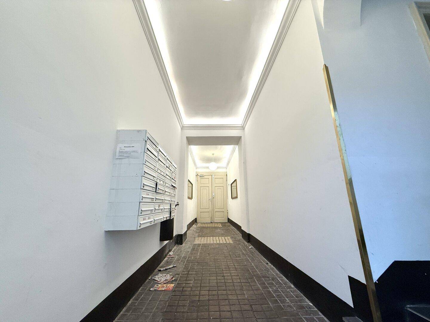 Eingangsbereich des Gebäudes mit Briefkästen und hohen Decken, einladend und gut gepflegt.