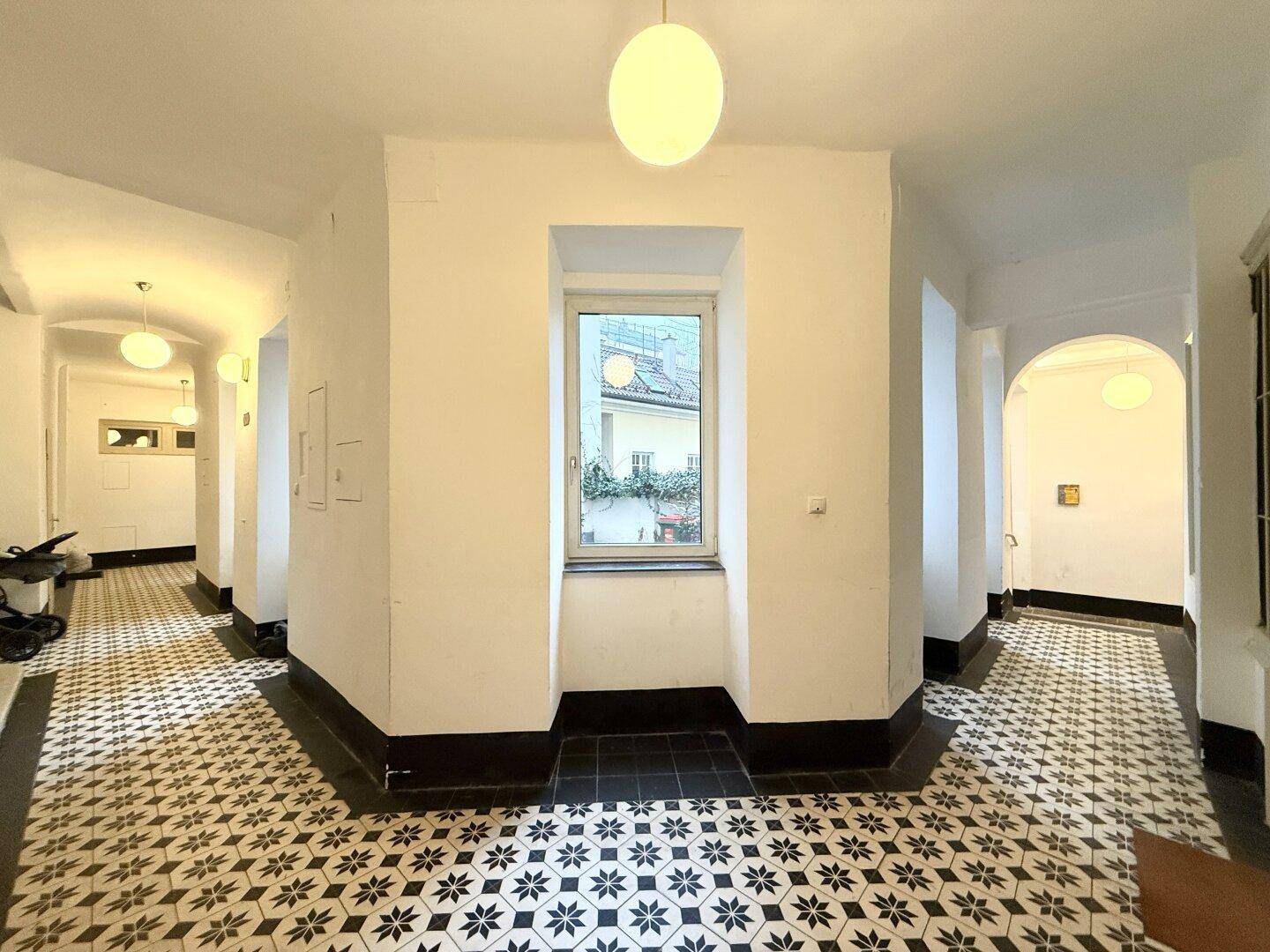 Heller Flur im Gebäude mit dekorativen Fliesen und Fenster, bietet eine angenehme Atmosphäre.