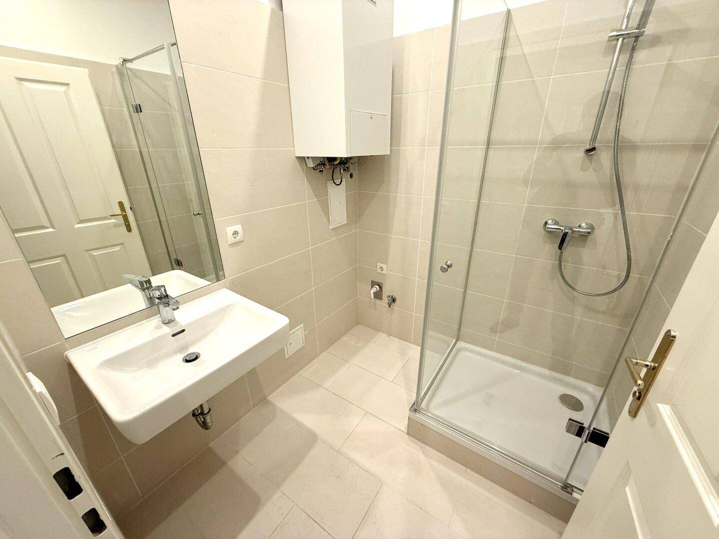 Modernes Badezimmer mit Duschkabine, Waschbecken und hellen Fliesen, bietet Komfort und Funktionalität.