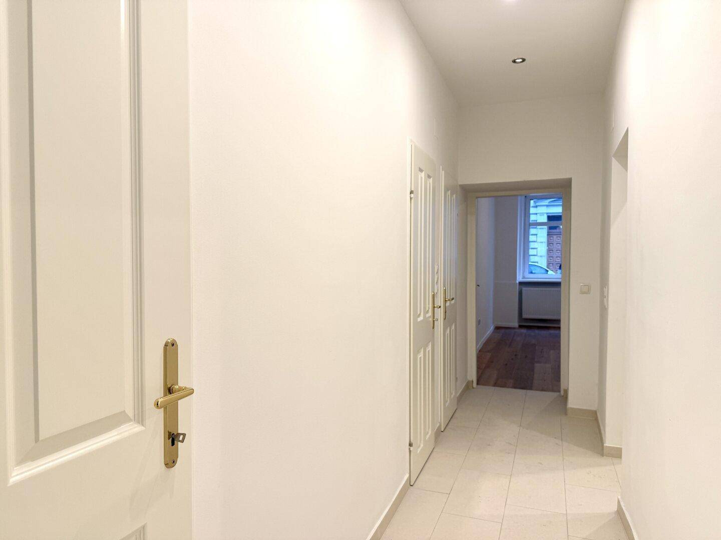 Heller Flur mit Fliesenboden und weißen Türen, der zu den verschiedenen Räumen führt.