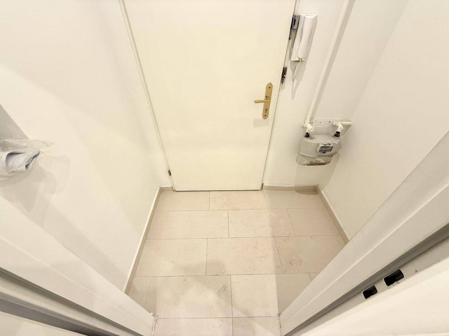 Kleiner Eingangsbereich mit Fliesenboden und Gegensprechanlage, funktional und ordentlich gehalten.