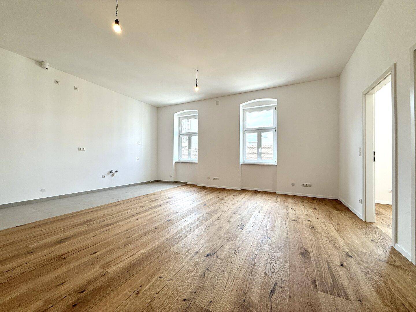 Heller, leerer Raum mit Holzboden und weißen Wänden, bereit für individuelle Gestaltung.