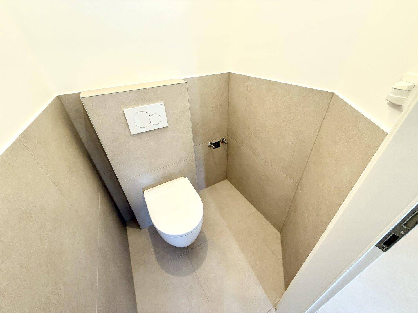 Kleines, modernes WC mit wandhängender Toilette und hellen Fliesen.