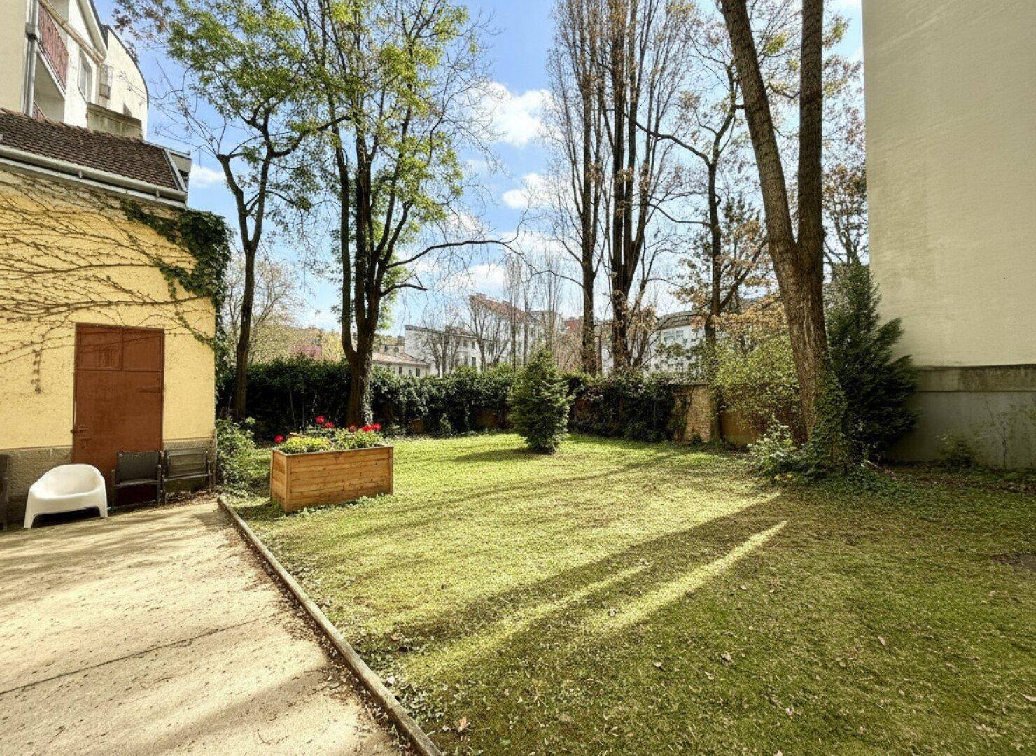 Grüner Gemeinschaftsgarten mit Rasenfläche und Bäumen, ideal zum Entspannen im Freien.