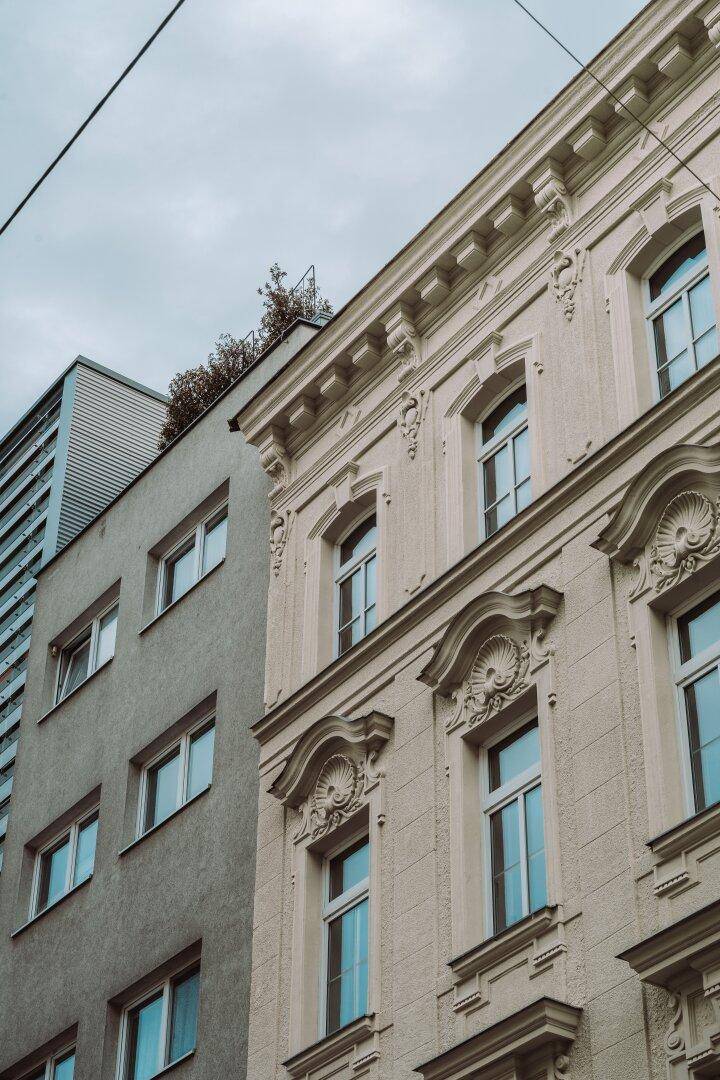 Nahaufnahme der historischen Fassade neben einem modernen Gebäude mit Flachdach und Begrünung.