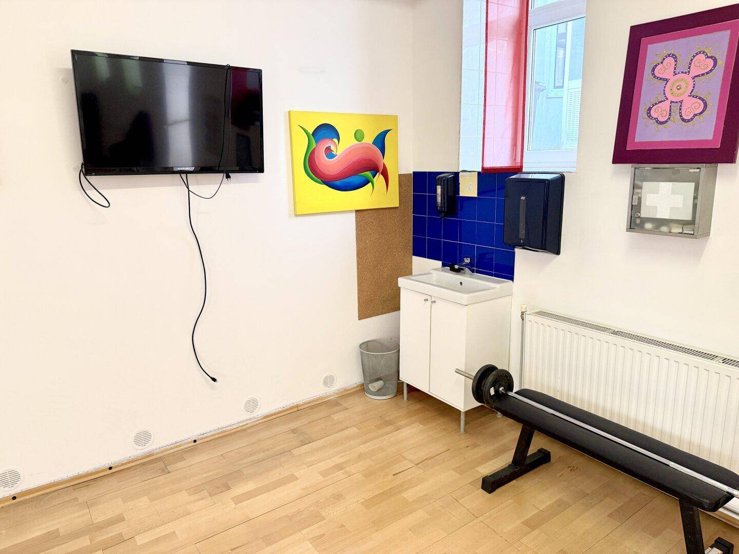 Trainingsbereich mit Waschbecken, Fernseher und Hantelbank, ideal für sportliche Aktivitäten.