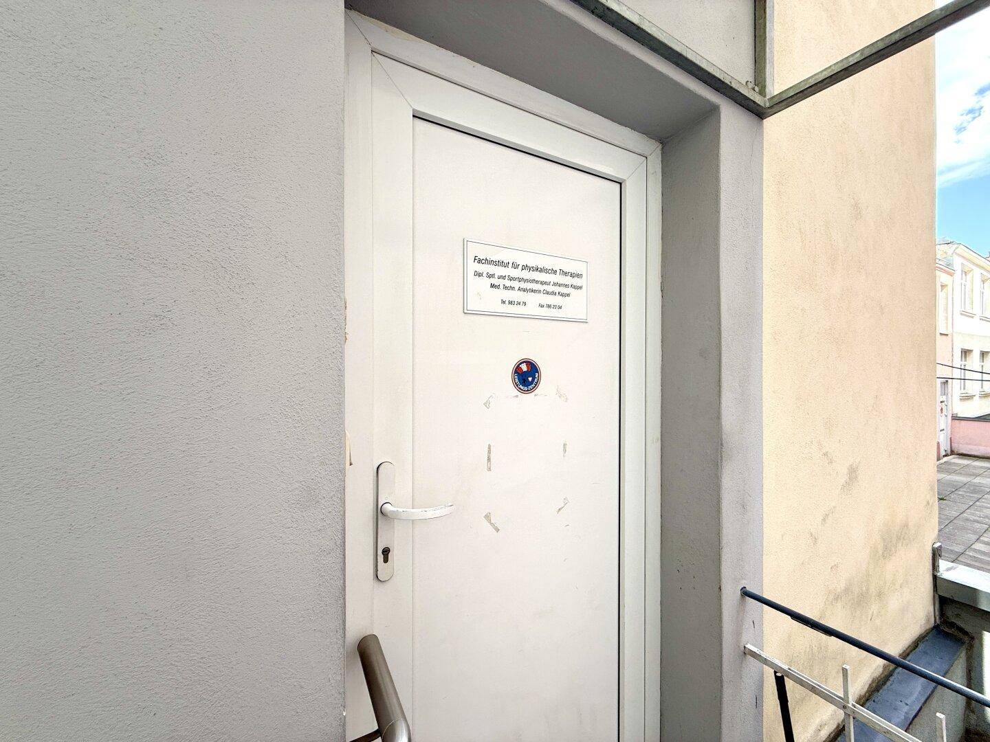 Eingangstür zu einer Praxis mit Beschilderung, gelegen in einem Außenbereich des Gebäudes.