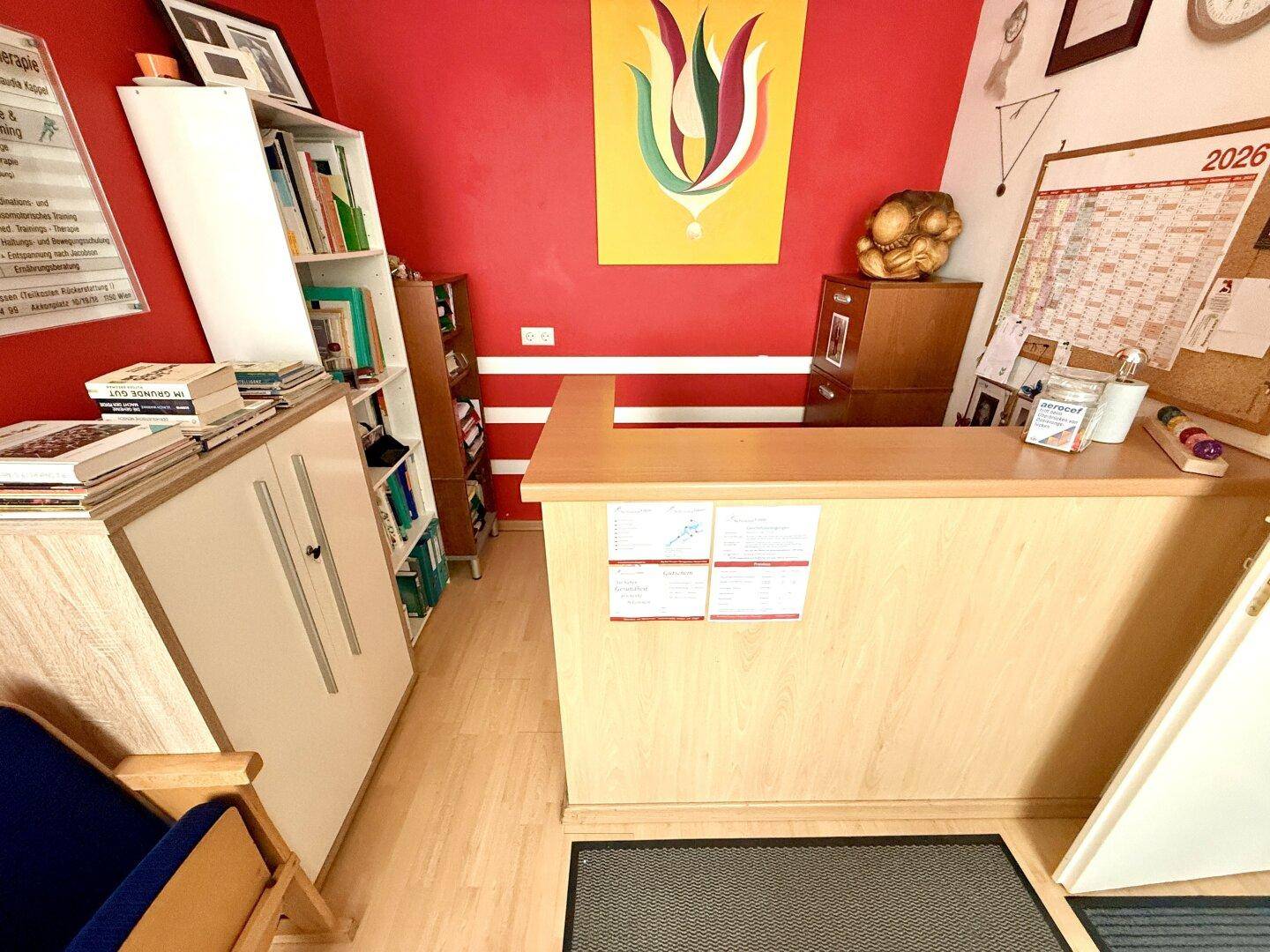 Detailansicht des Empfangsbereichs mit Holztheke, Regalen und farbenfroher Wandkunst.