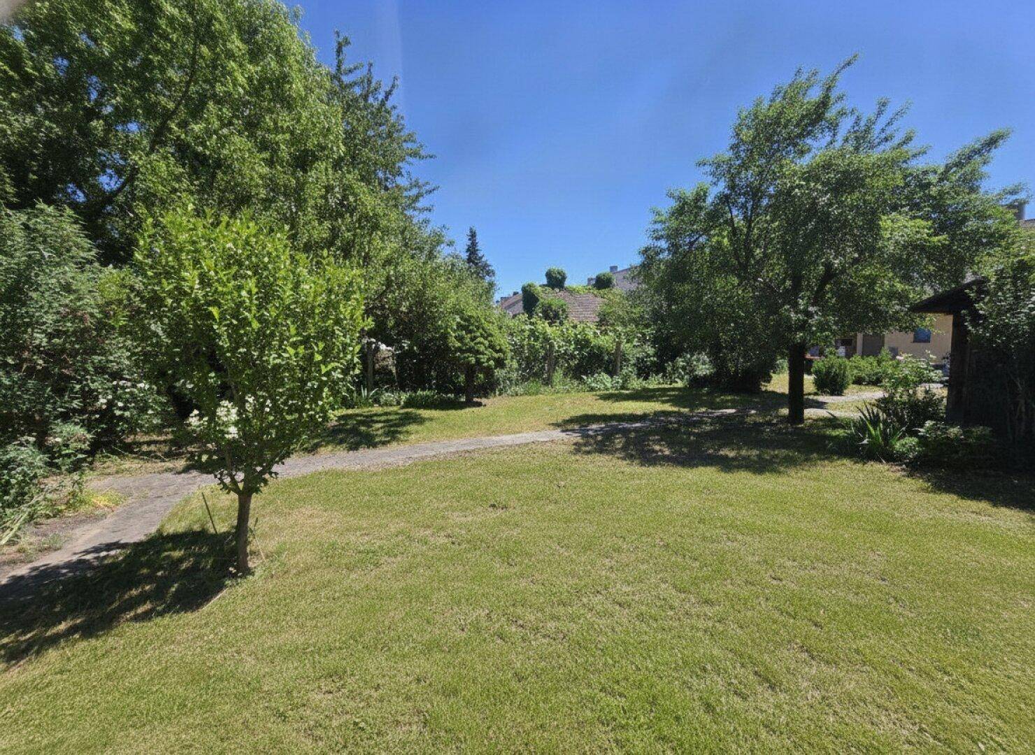 Weitläufiger Garten mit viel Grün und Blick auf die umliegende Bebauung.