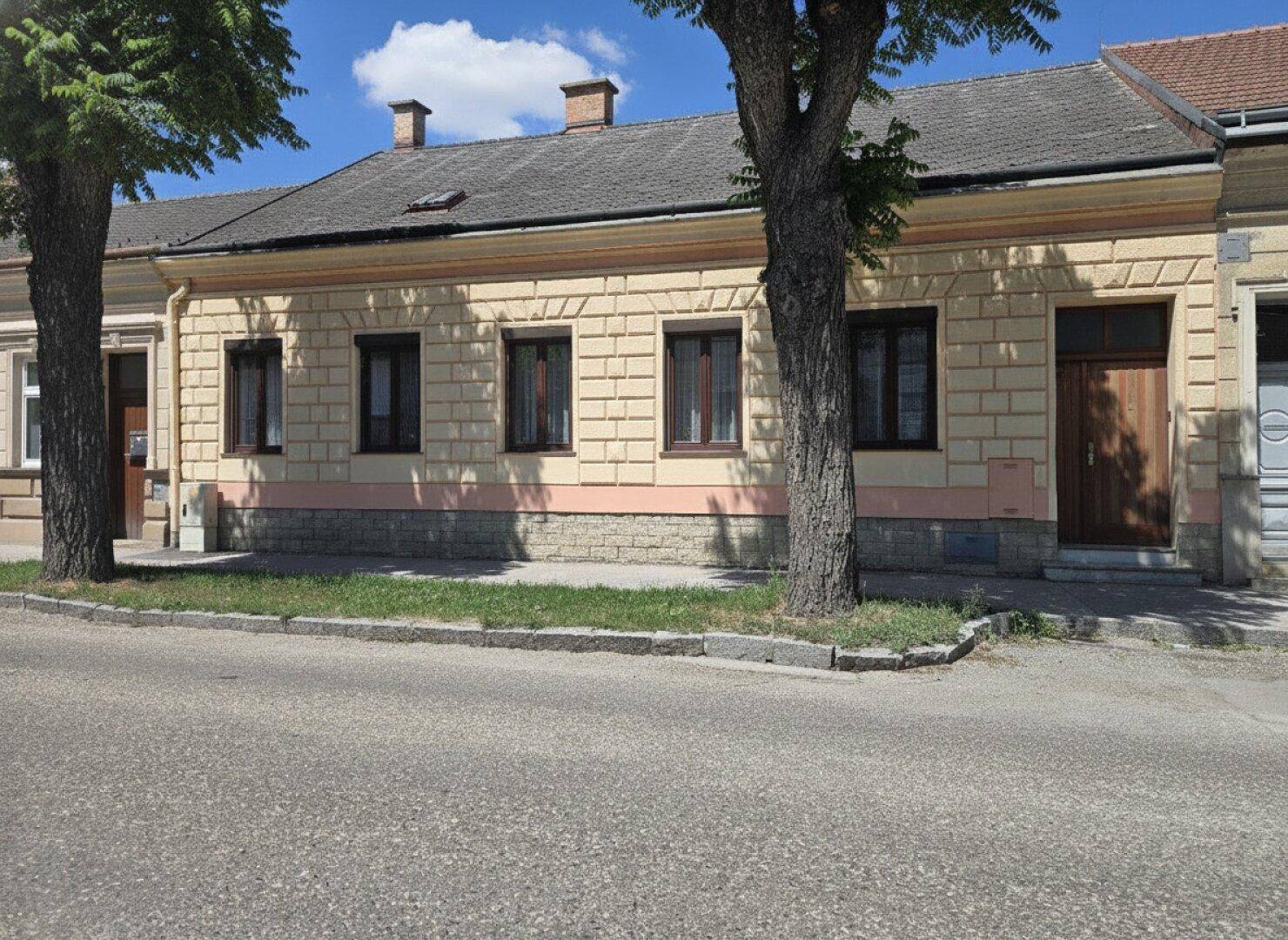 Fassade eines traditionellen Gebäudes mit mehreren Fenstern und Holztüren zur Straße hin.