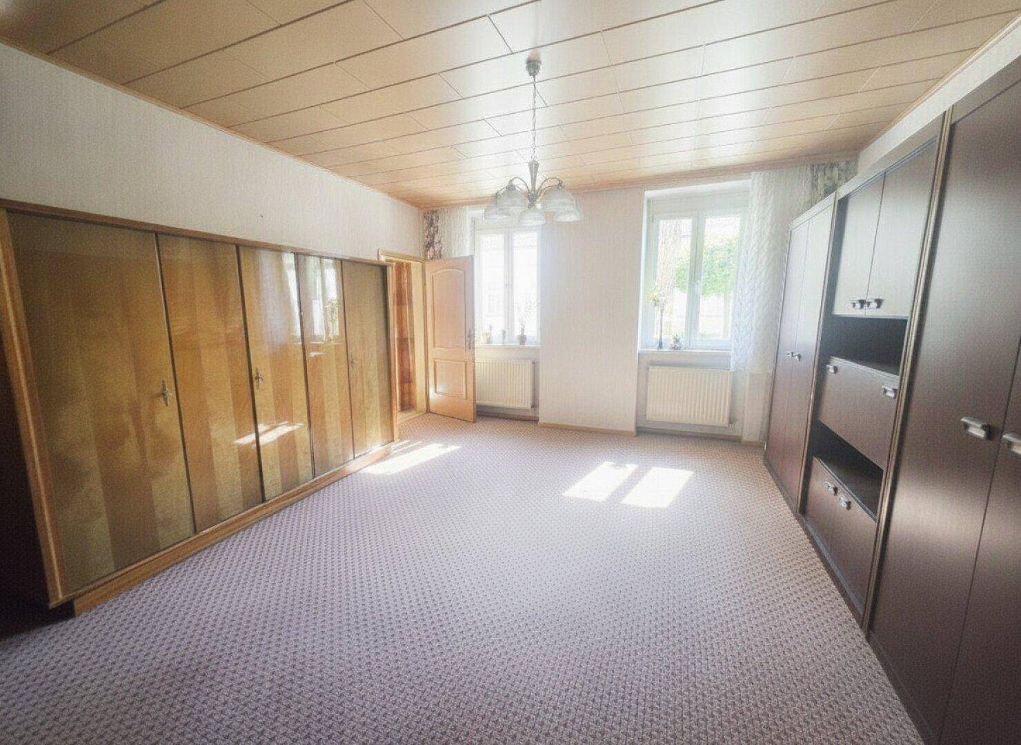 Schlafzimmer mit Teppichboden, Holzdecke und großen Kleiderschränken.