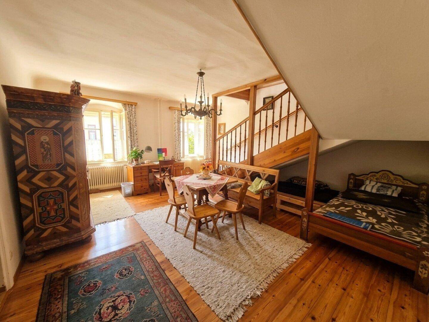 Gemütlicher Wohn- und Essbereich mit Holzboden, traditionellen Möbeln und Dachschräge.