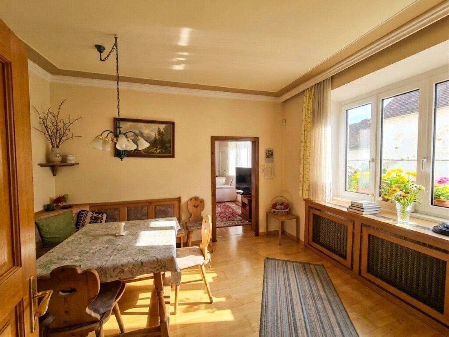 Heller Essbereich mit Holzboden, traditionellen Möbeln und Blick auf den Innenhof.