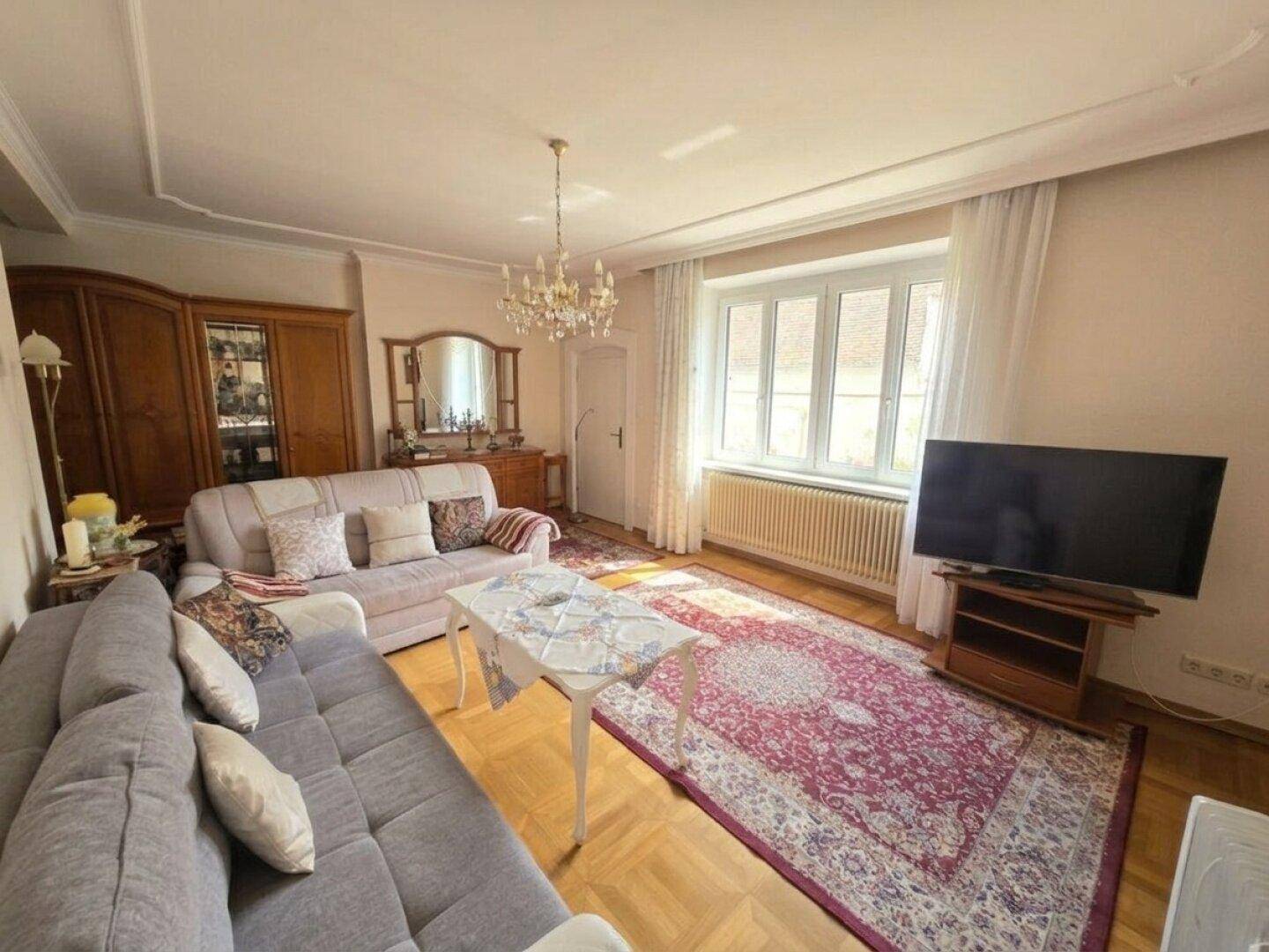 Geräumiges Wohnzimmer mit Parkettboden, bequemen Sofas und einem großen Fenster.