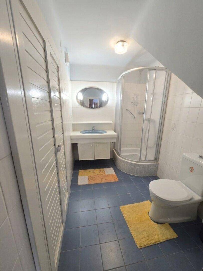 Kleines Badezimmer mit blauen Fliesen, Duschkabine und Dachschräge.